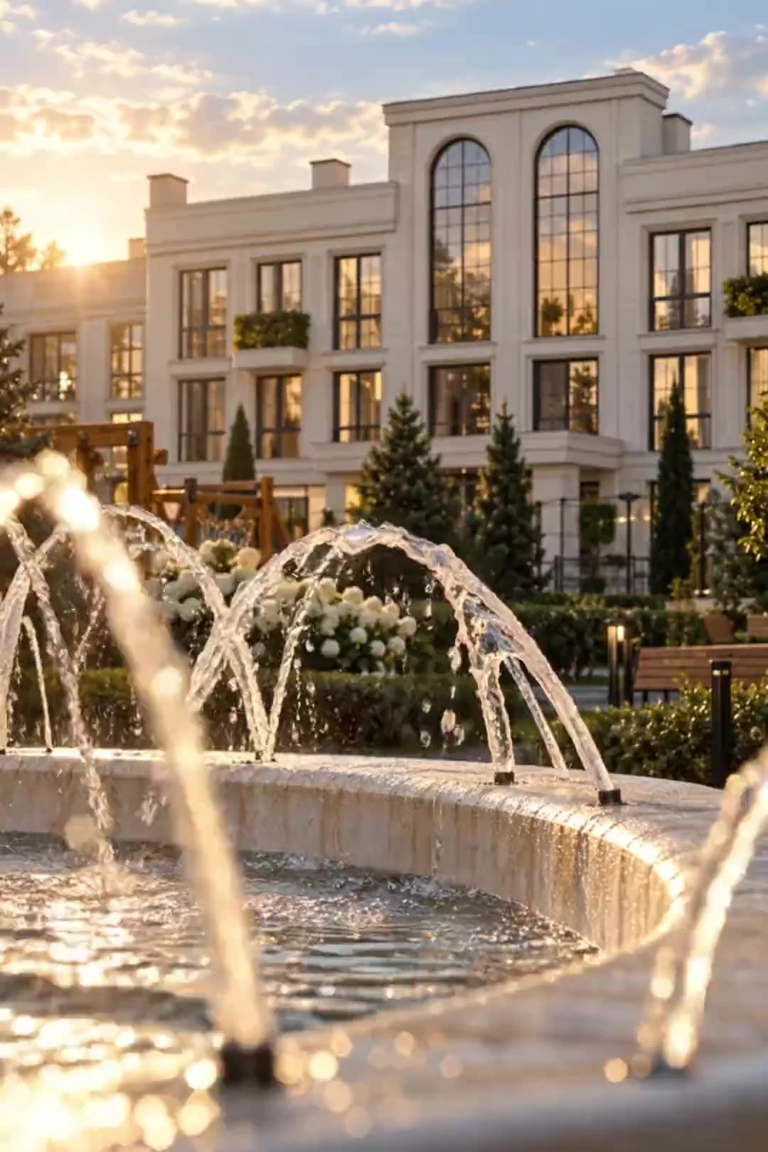 Klassische Fassade mit Bogenfenstern hinter einem Brunnen bei Sonnenuntergang