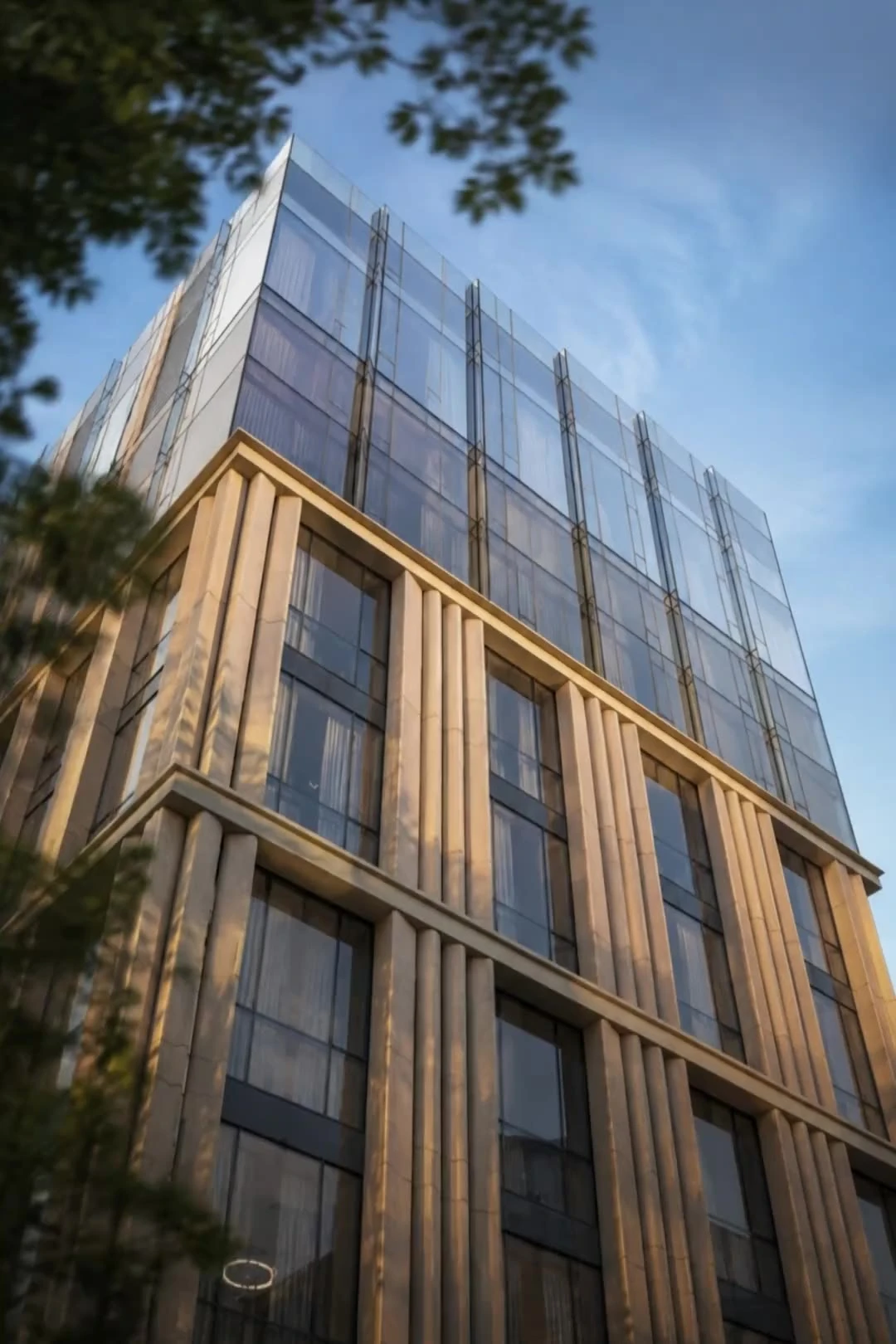 Fassade mit Steinlamellen unter einem Glasaufbau im Abendlicht