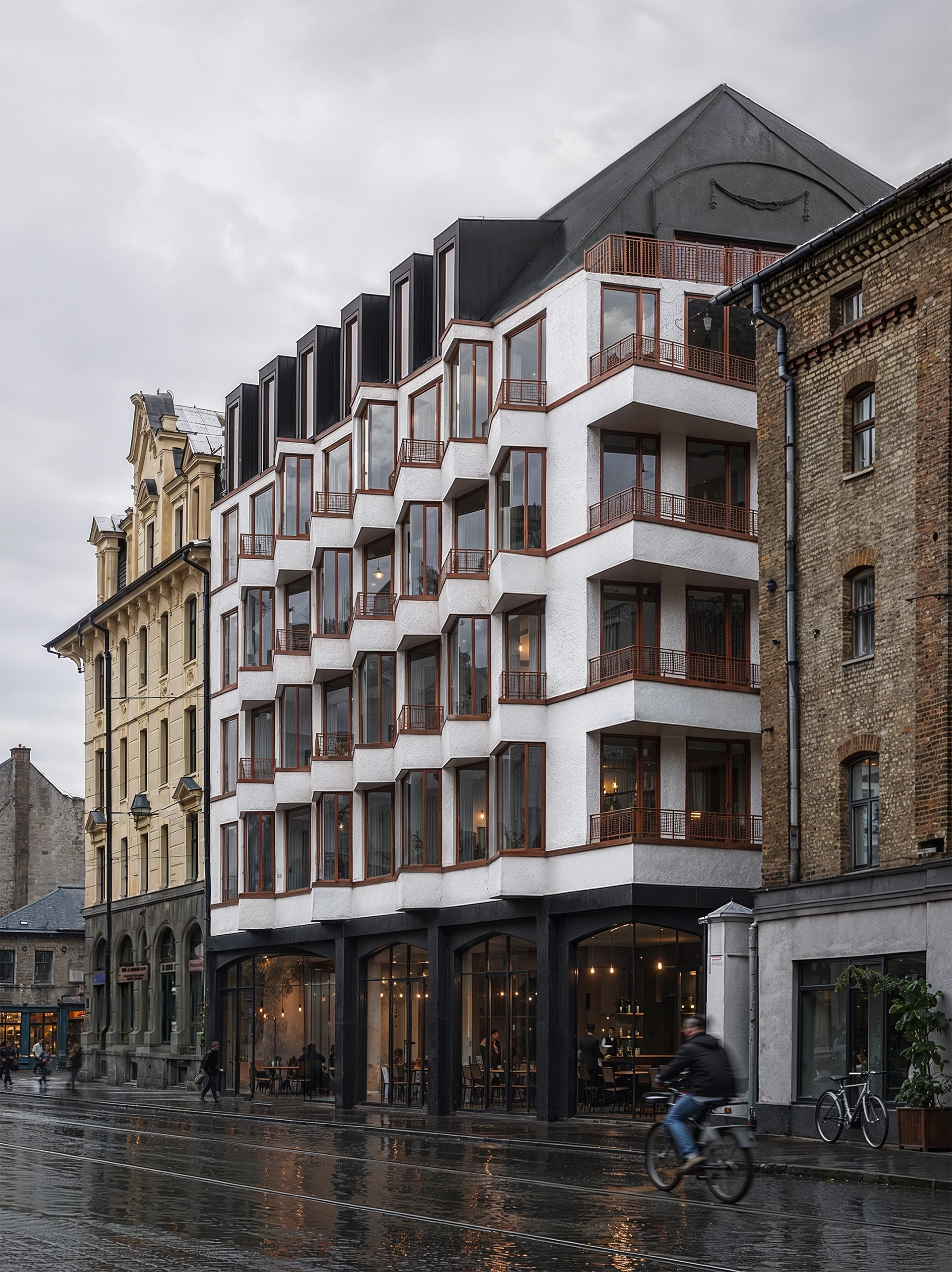 White stepped facade with red balcony rails on a rainy evening